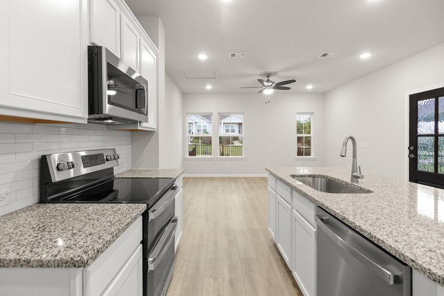 The property features a kitchen with white cabinetry, granite countertops, a stainless steel microwave, and a stainless steel range