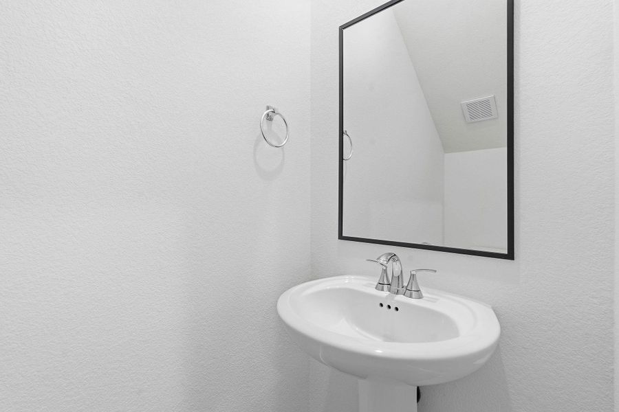 Pedestal sink with chrome faucet, framed mirror, and white textured walls Pedestal sink with chrome faucet, framed mirror, and white textured walls