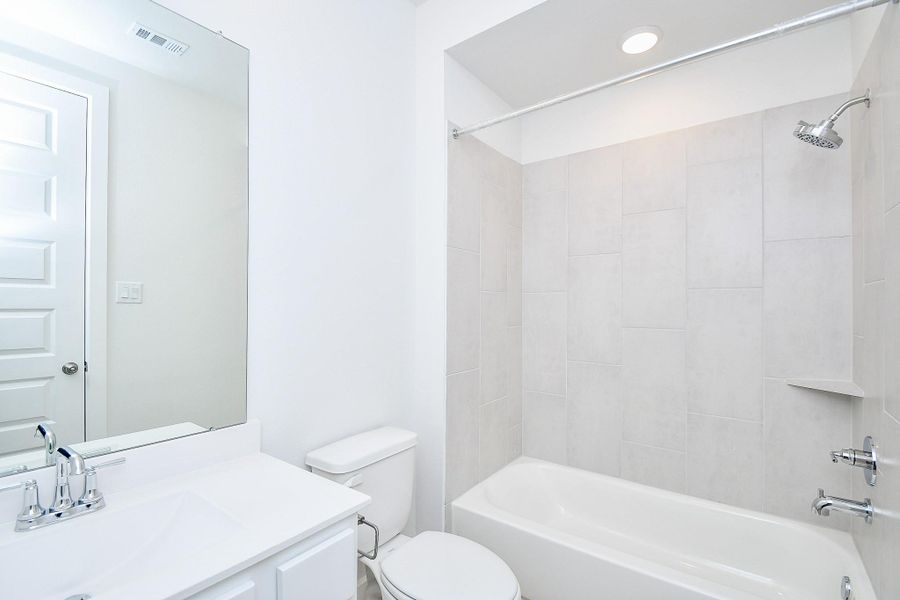 A modern bathroom with a sleek shower-tub combo, bright lighting, and a clean aesthetic.
