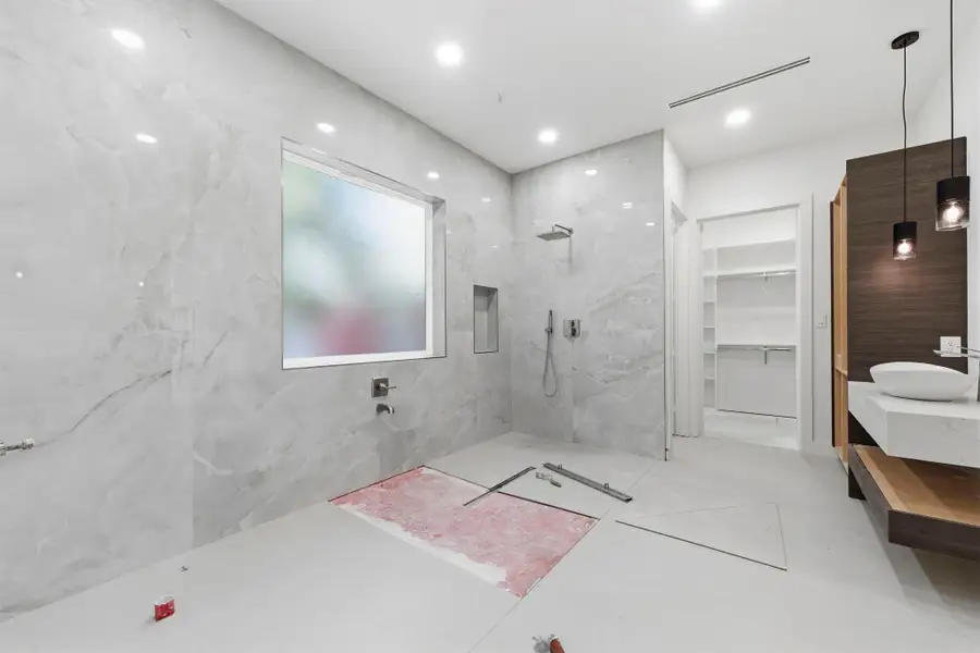 This photo showcases the primary bathroom's modern design, highlighting the entrance to a spacious walk-in closet. This photo showcases the primary bathroom's modern design, highlighting the entrance to a spacious walk-in closet.