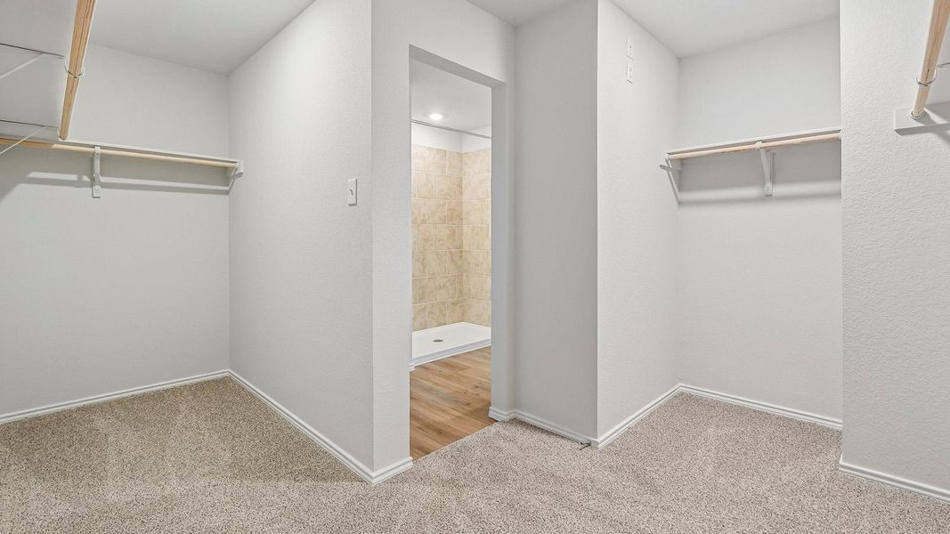 Ample closet space with practical shelving connects directly to a tiled shower, offering convenience.