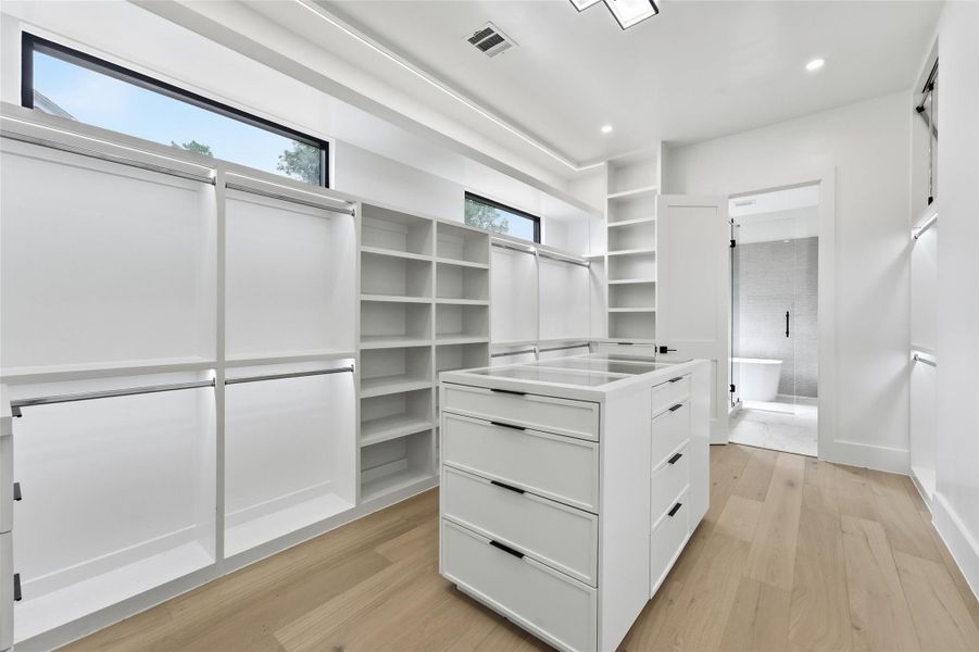 An expansive custom walk-in closet with abundant hanging space, built-in drawers, open shelving, and a central storage island for effortless organization.