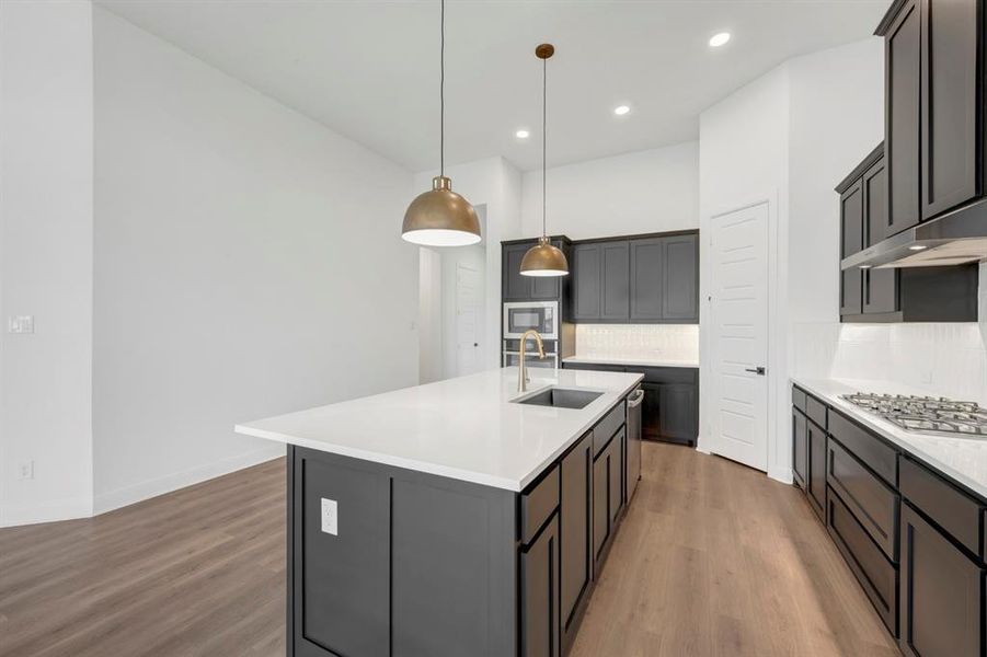 Kitchen featuring backsplash, dark wood-style flooring, and light stone counters