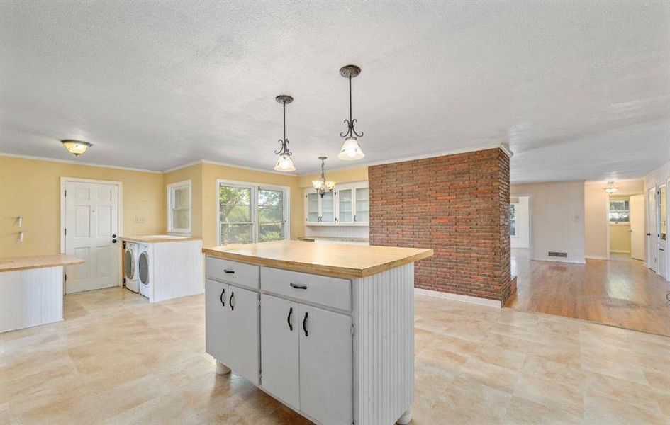 Kitchen with white cabinetry, light countertops, decorative light fixtures, a kitchen island, and a textured ceiling