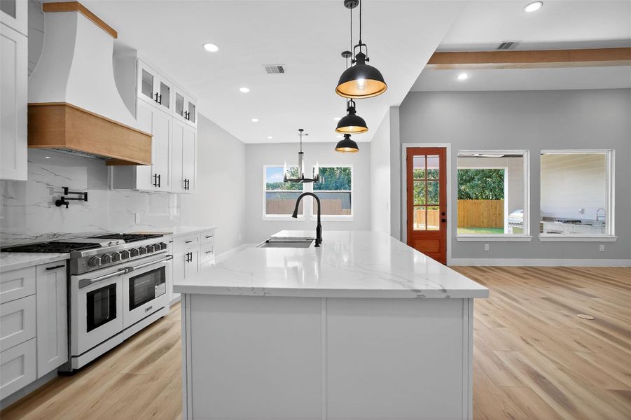The chef’s dream kitchen features an oversized granite island, six burner range with grill and double oven