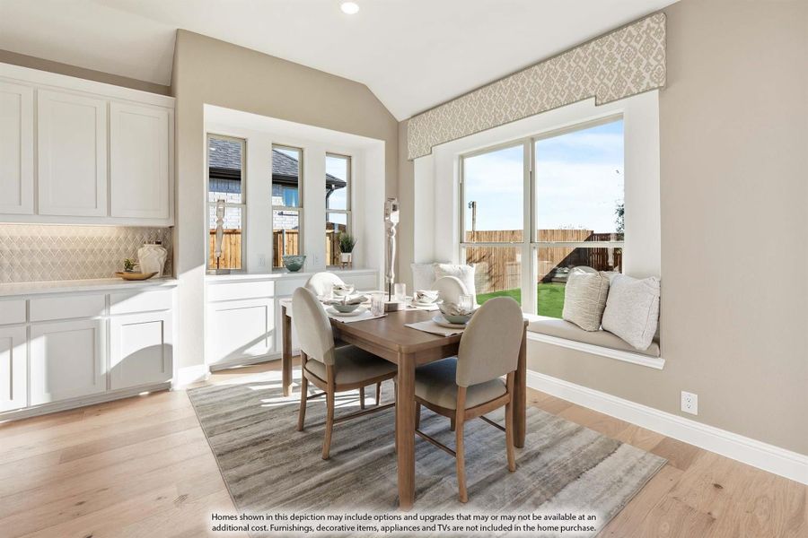 Dining nook with wood table, four chairs, window seat, and white cabinets on hardwood floors
