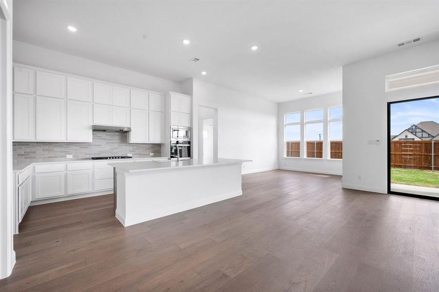 Kitchen featuring an island with sink, white cabinetry, exhaust hood, and dark hardwood / wood-style flooring