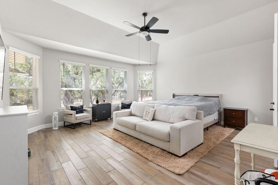 Primary suite featuring bay windows, light brown tile floors, and high vaulted ceiling