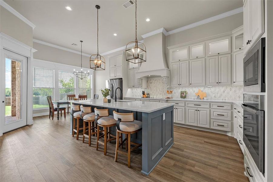 Open-concept kitchen with large center island, farmhouse sink, breakfast bar, and built-in cabinetry. Open-concept kitchen with large center island, farmhouse sink, breakfast bar, and built-in cabinetry.