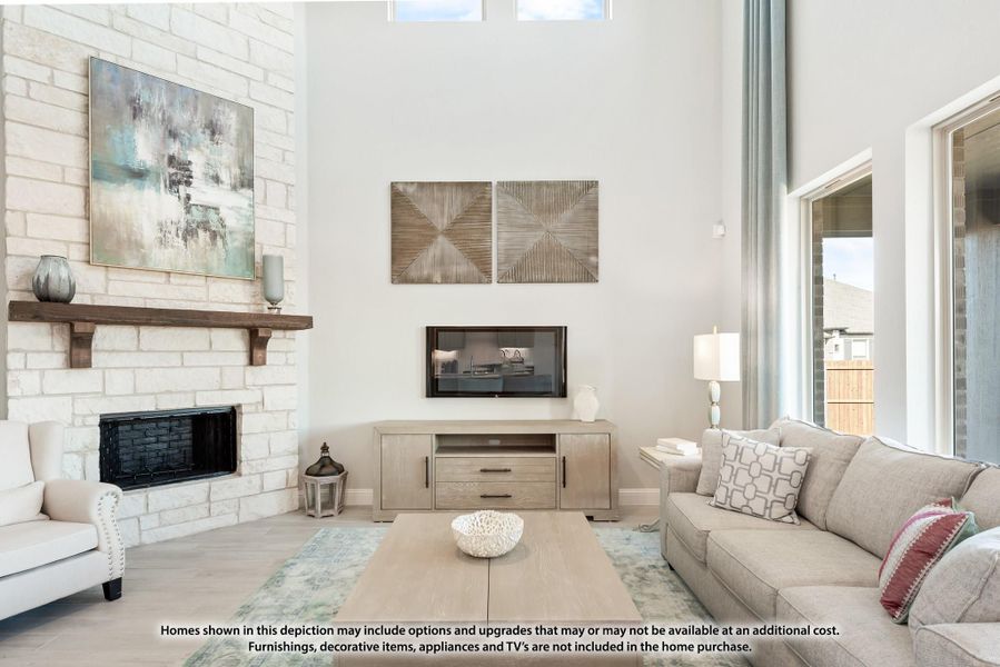 Living room with two-story white stone fireplace, wall-mounted TV, and neutral sofa seating