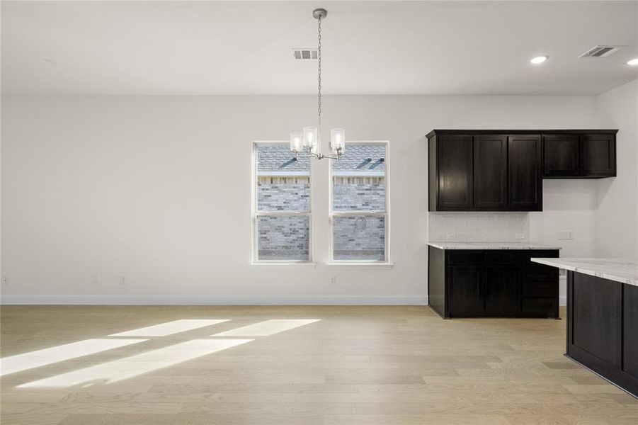 Unfurnished dining area with light wood-style flooring, a chandelier, and recessed lighting