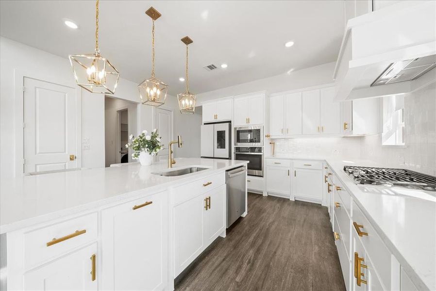 Kitchen with visible vents, decorative backsplash, stainless steel appliances, premium range hood, and a sink