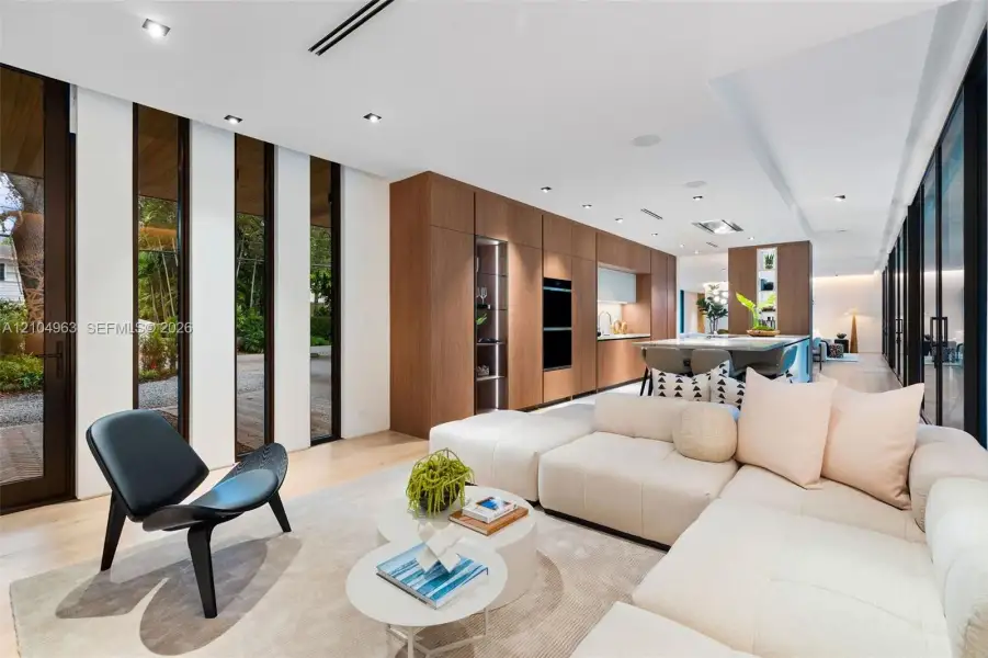 Open-concept space featuring wood-finish flooring, floor-to-ceiling windows, recessed lighting, and full-height wood cabinetry with built-in wall ovens