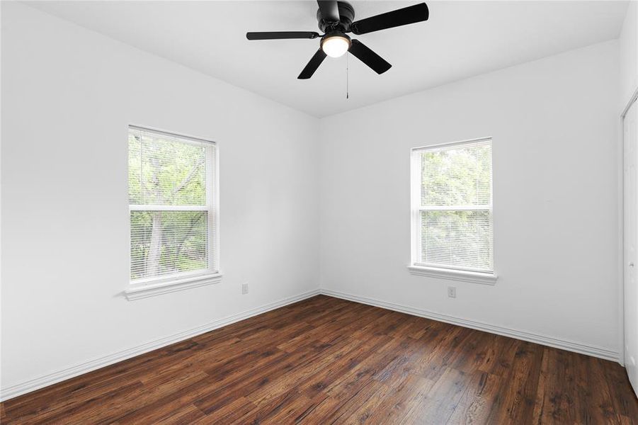 Spare room with dark wood-style flooring and a ceiling fan Spare room with dark wood-style flooring and a ceiling fan