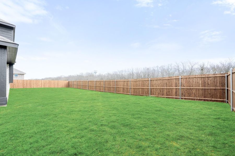 Spacious backyard with green grass lawn and full wood privacy fence enclosing the yard