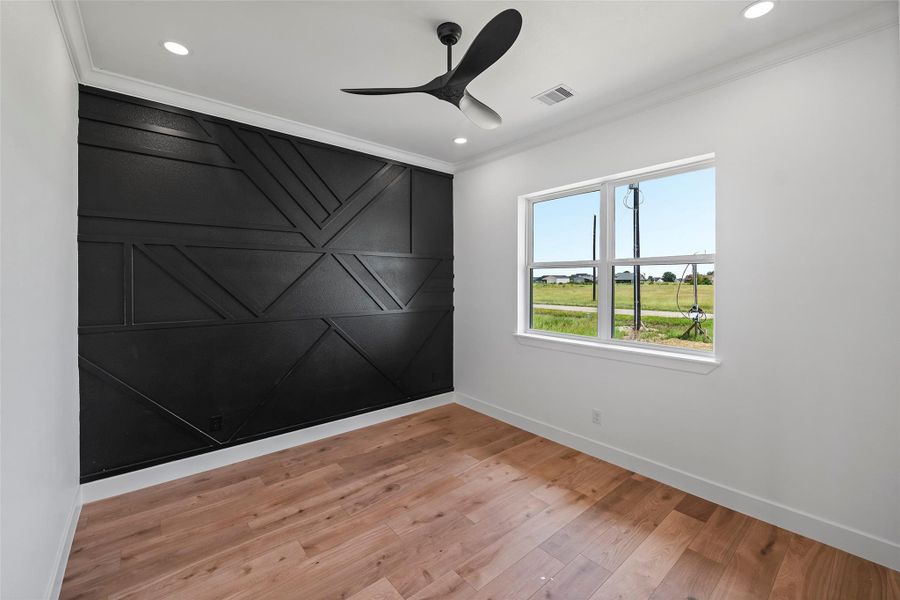 Modern office space featuring sleek black accent wall, large window for natural light, and stylish ceiling fan—perfect for productivity and inspiration.