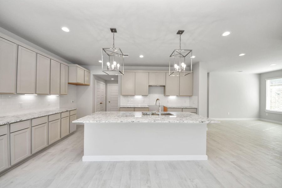 The kitchen is a culinary haven, featuring granite countertops, a tile backsplash, stainless steel appliances, 42” upper cabinets, and undercabinet lighting. Sample photo of completed home with similar floor plan. Actual colors and selections may vary.