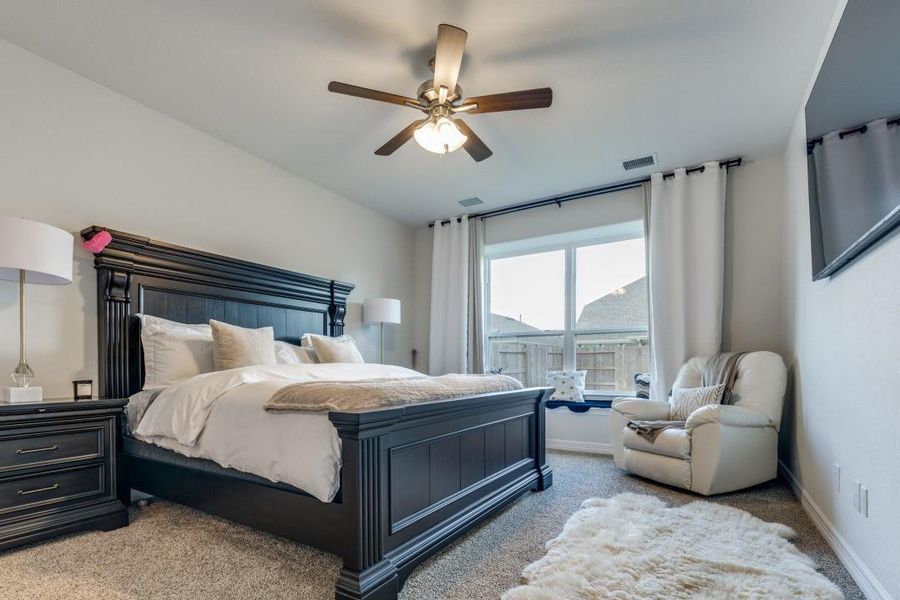 Ample natural light from a large window, white curtains, and a ceiling fan for comfort.