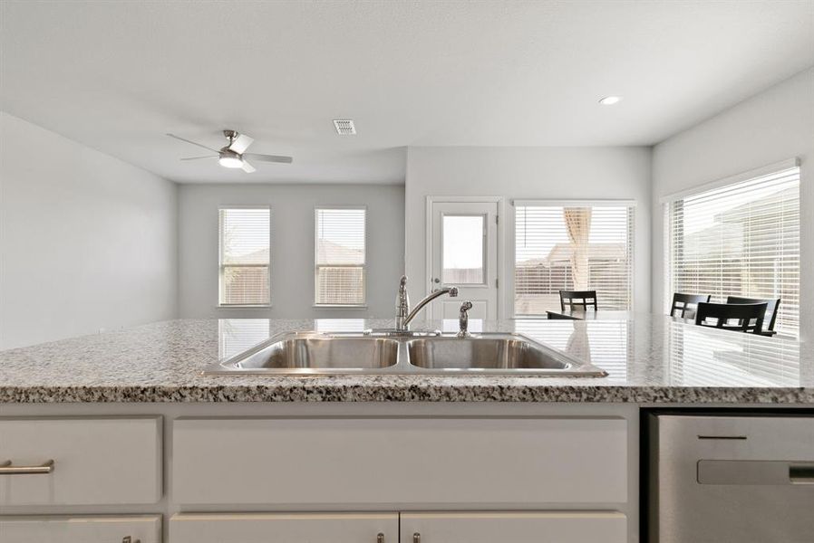 Kitchen with stainless steel dishwasher, white cabinets, light stone countertops, a ceiling fan, and recessed lighting