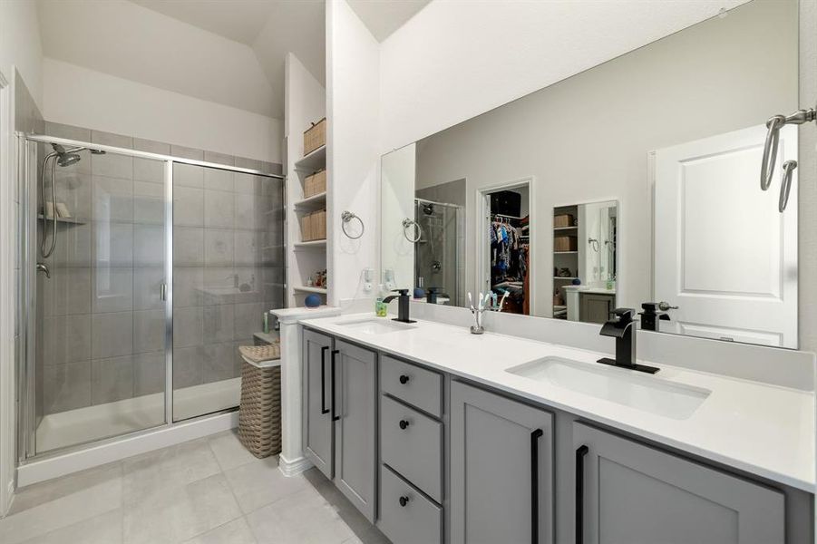 Full bathroom with a walk in closet, a stall shower, double vanity, and light tile patterned floors Full bathroom with a walk in closet, a stall shower, double vanity, and light tile patterned floors