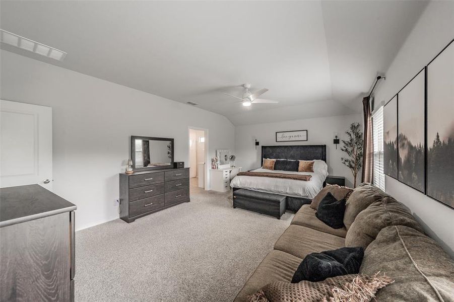 Spacious bedroom featuring vaulted ceilings, light gray carpeting, and a ceiling fan