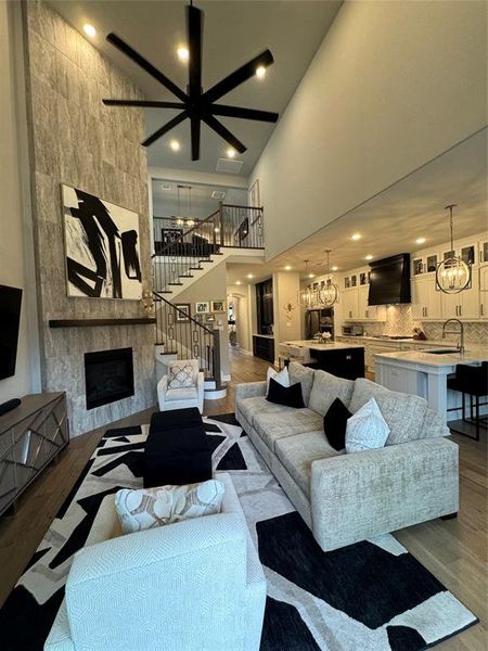 Living room featuring a chandelier, dark wood-type flooring, a fireplace, a high ceiling, and sink