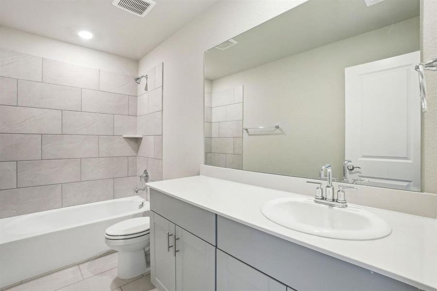 Full bathroom featuring shower combination, vanity, and light tile patterned floors Full bathroom featuring shower combination, vanity, and light tile patterned floors