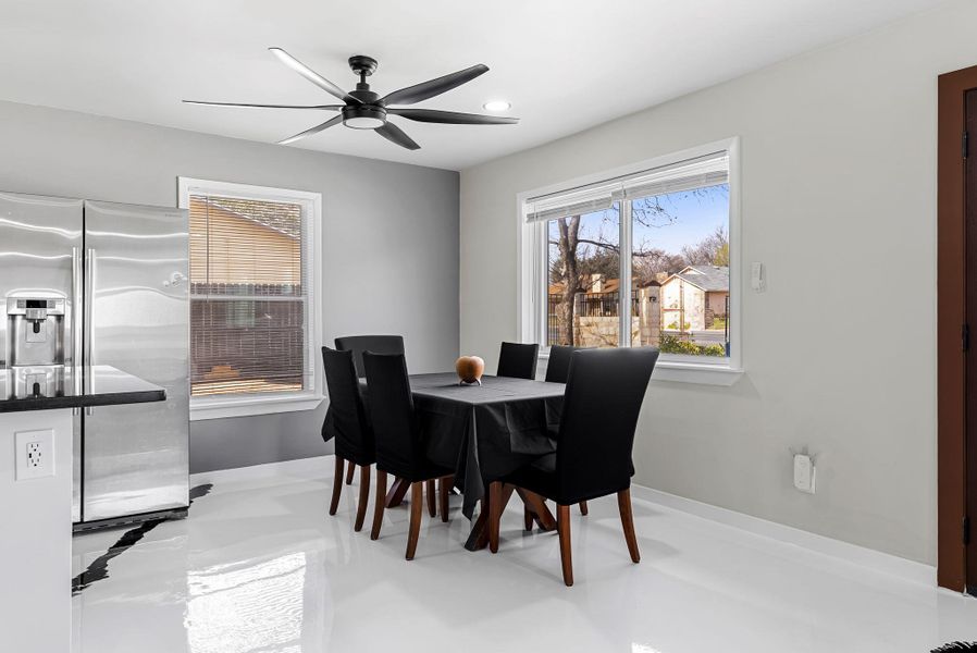 Dining space featuring a ceiling fan, plenty of natural light, and concrete floors