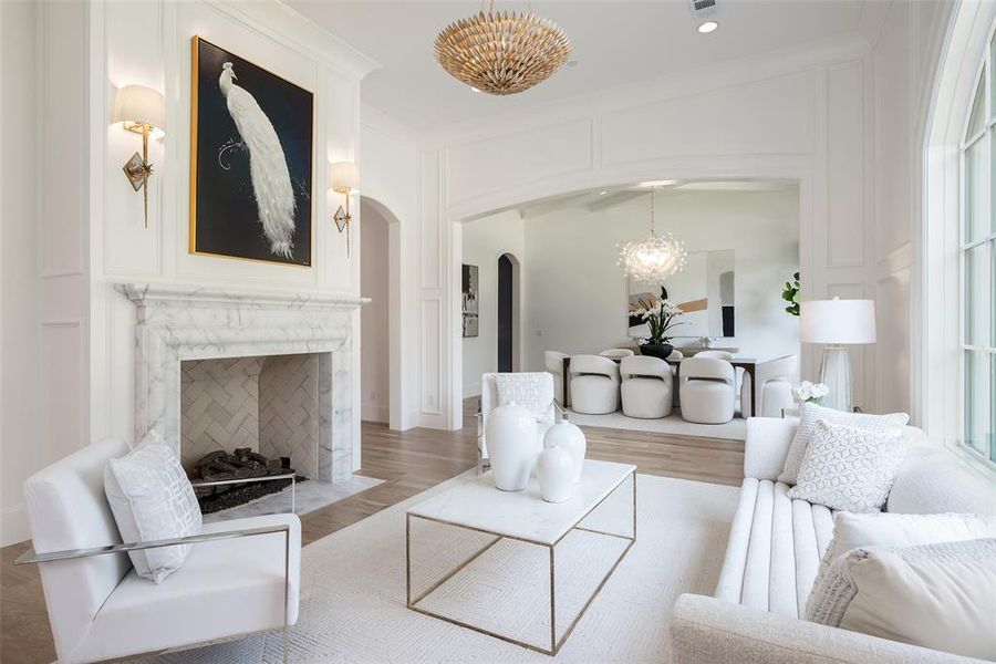 Living room with a high end fireplace, a chandelier, light hardwood / wood-style flooring, and a healthy amount of sunlight