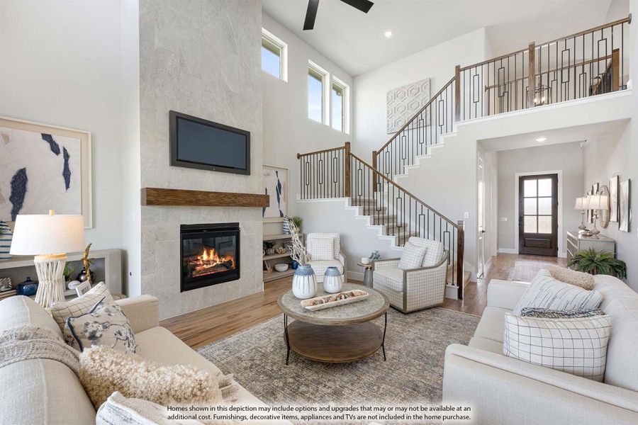 Two-story living room with stone fireplace, wood mantel, staircase, and hardwood floors