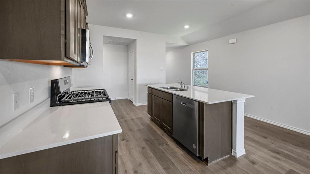 Open-concept kitchen featuring an island with built-in sink and stainless steel dishwasher