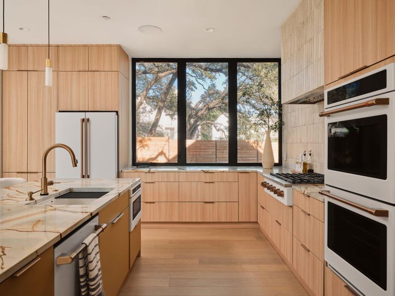Kitchen featuring light wood finish cabinets, light stone countertops, and modern cabinets