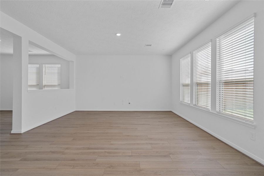 Bring family and friends together in this beautiful family room! It features high ceilings, recessed lighting, custom paint, vinyl plank flooring, and large windows that fill the space with natural light all day long.