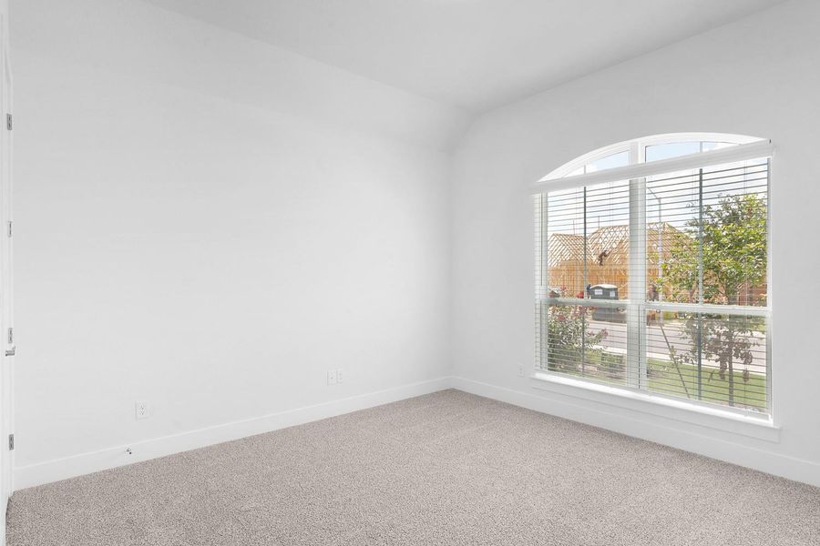 A quiet secondary bedroom features an arched window overlooking the neighborhood.