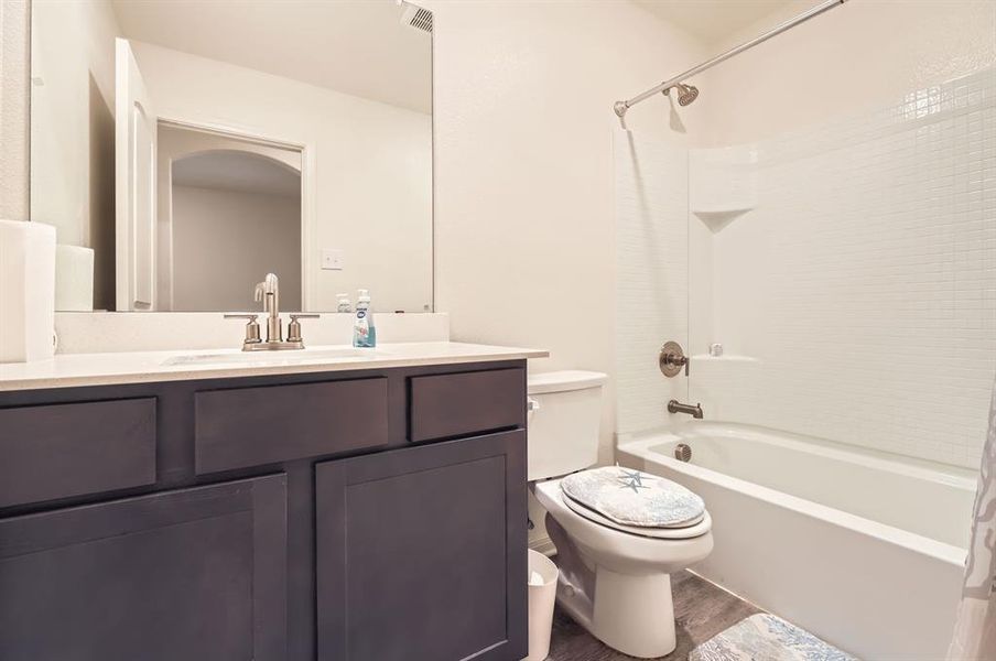 Full bathroom with toilet, vanity, shower / bath combo, and hardwood / wood-style floors