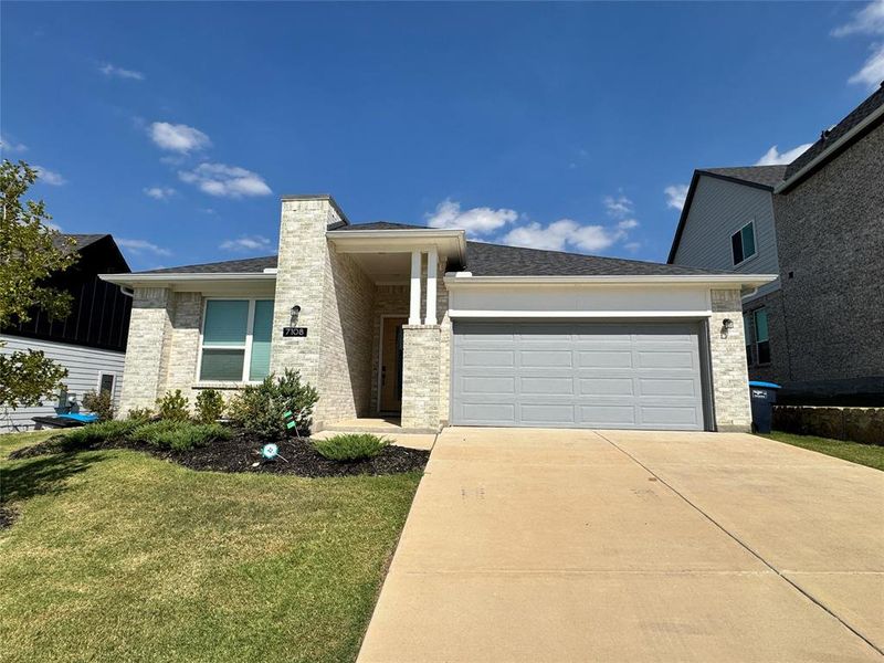 Front facade with brick siding, an attached garage, concrete driveway, roof with shingles, and a front lawn Front facade with brick siding, an attached garage, concrete driveway, roof with shingles, and a front lawn