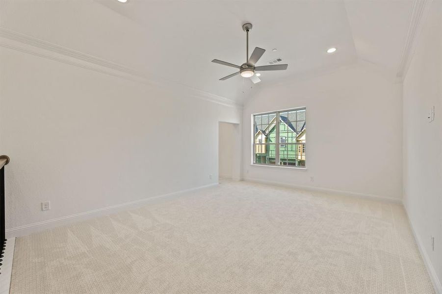 Carpeted spare room with ornamental molding, vaulted ceiling, and ceiling fan