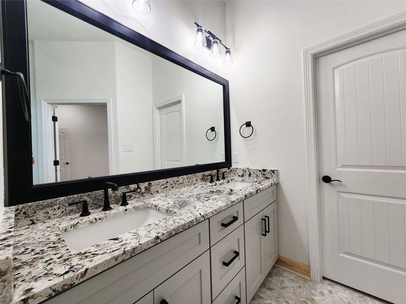 Double vanity with stone countertop, undermount sinks, and matte black fixtures