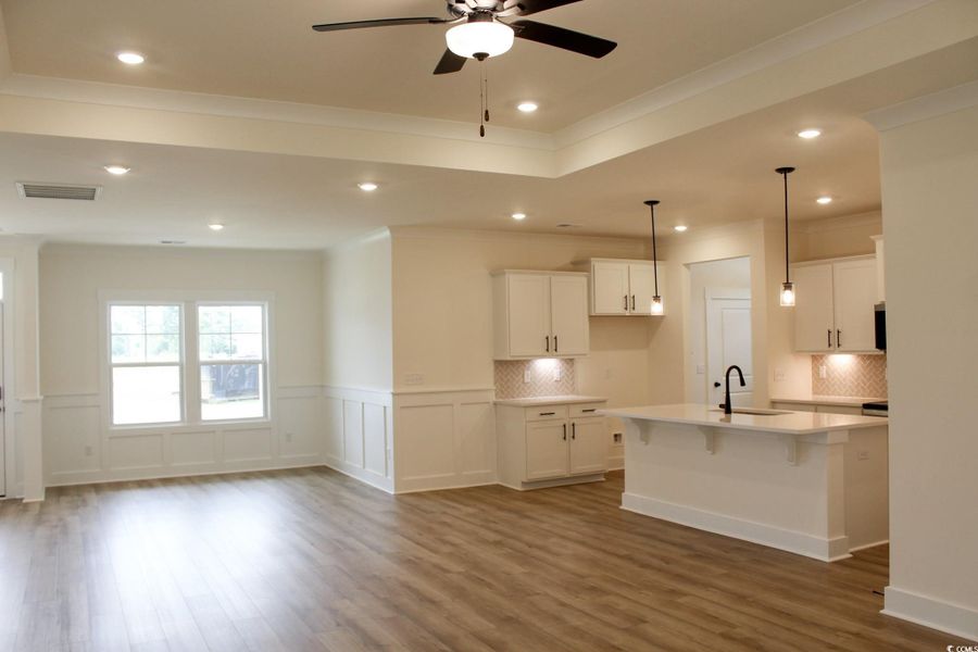 Kitchen featuring white cabinets, a kitchen breakfast bar, ornamental molding, recessed lighting, and decorative light fixtures