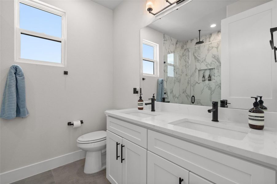 Dual vanity with pristine countertops and an elegantly tiled shower create a spa-like retreat. Dual vanity with pristine countertops and an elegantly tiled shower create a spa-like retreat.