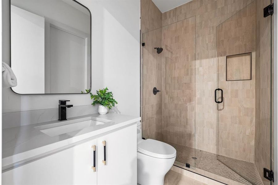 Bathroom featuring vanity, toilet, and a shower with door