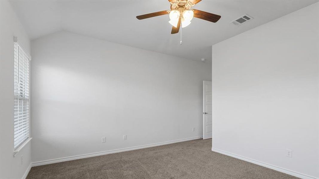 Empty room with carpet floors, ceiling fan, and vaulted ceiling