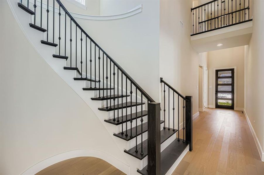 Staircase with wood finished floors, a high ceiling, and recessed lighting