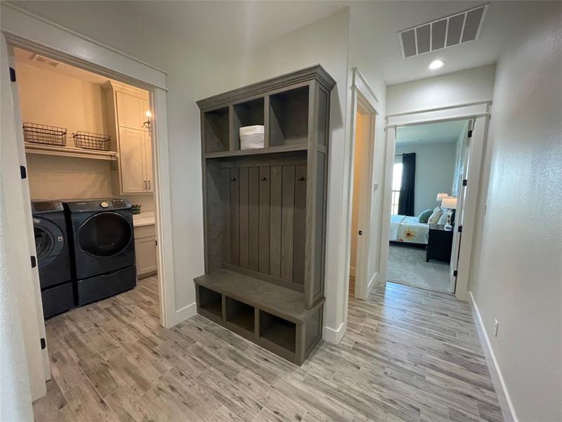 Mudroom featuring visible vents, baseboards, light wood finished floors, and washing machine and dryer