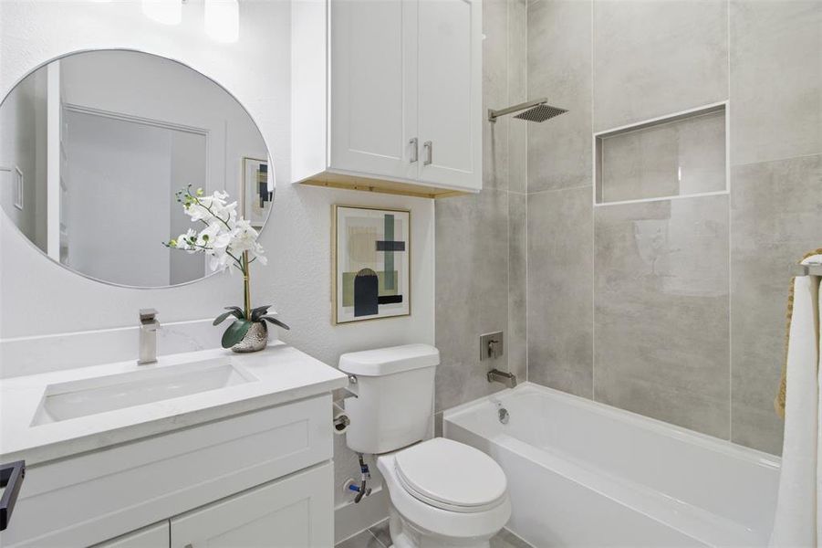 Bathroom featuring a white vanity with an integrated sink, a rectangular soaking tub, and floor-to-ceiling grey wall tile