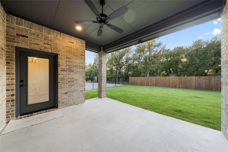 Fenced backyard with a patio and a ceiling fan
