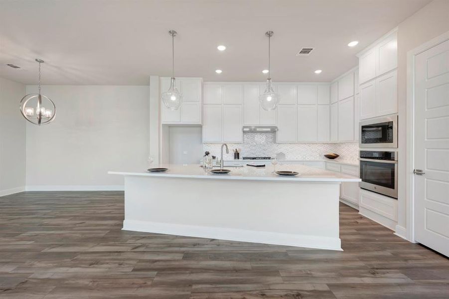 Kitchen featuring white cabinets, stainless steel oven, a center island with sink, and dark wood-style flooring