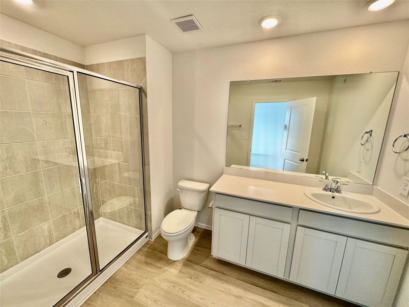 Full bathroom featuring light wood-type flooring, vanity, a stall shower, and recessed lighting