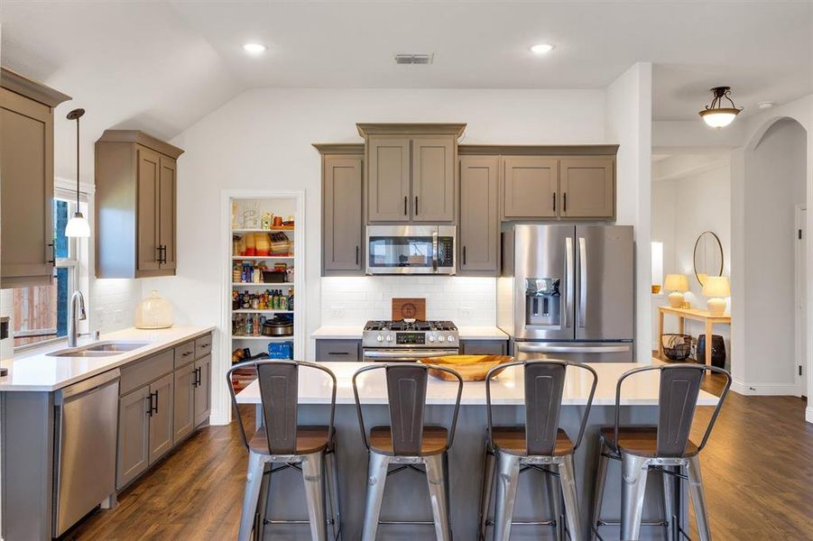 Kitchen featuring dark hardwood / wood-style floors, sink, appliances with stainless steel finishes, and vaulted ceiling