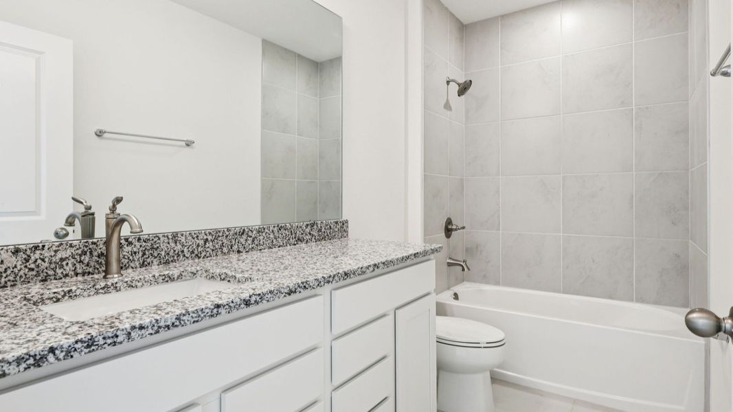 Bathroom with granite Countertops and white cabinets in the Baker by DRB Homes in Willowbrook North